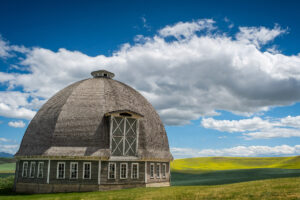 A round bard with yellow canola field in the background